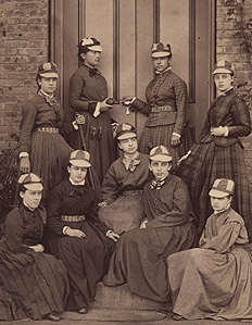 1876 photograph of The Resolutes, Vassar College's first baseball team. The women in this sepia photo sit in front of a brick building wearing long, full skirts and baseball caps.